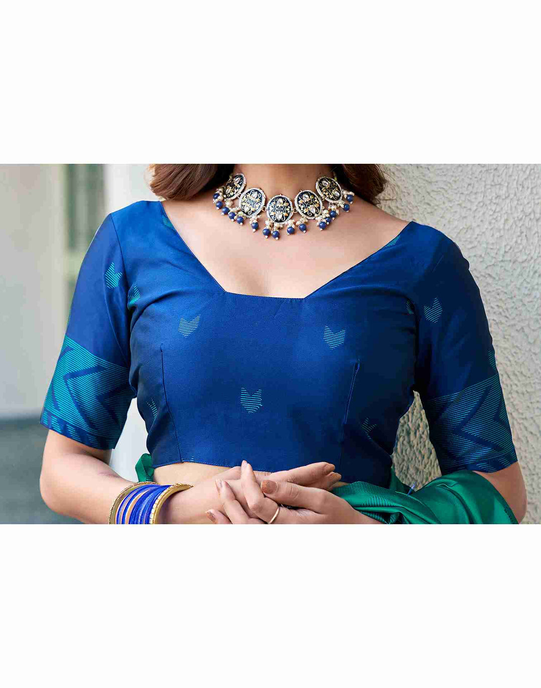 Close-up of model in navy blue silk blouse showing teal heart butta motifs, square neck, and chevron sleeve border