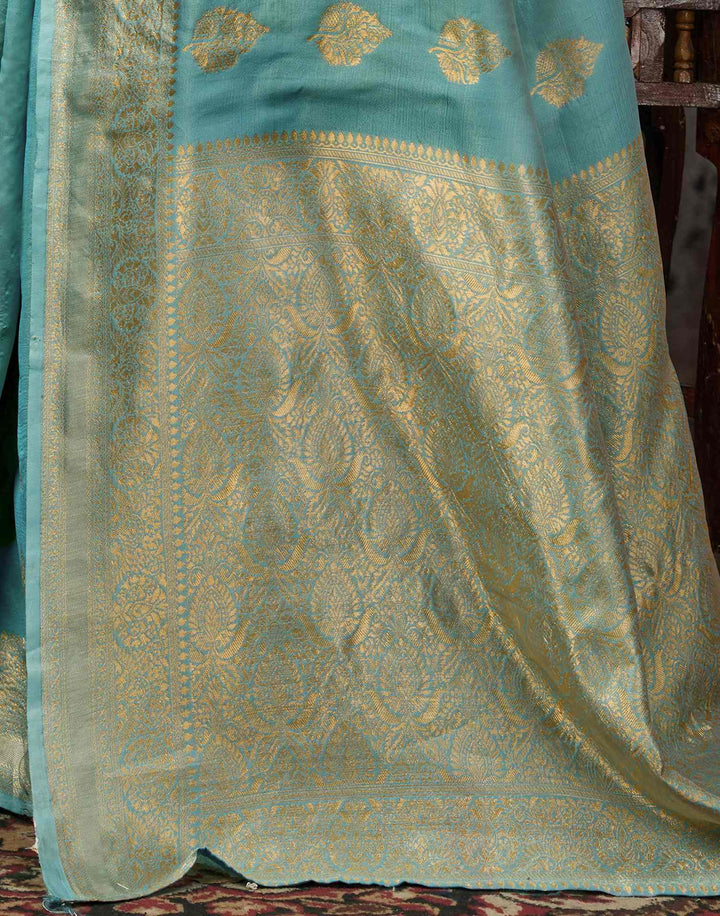 Model leaning against carved wooden door in teal saree
