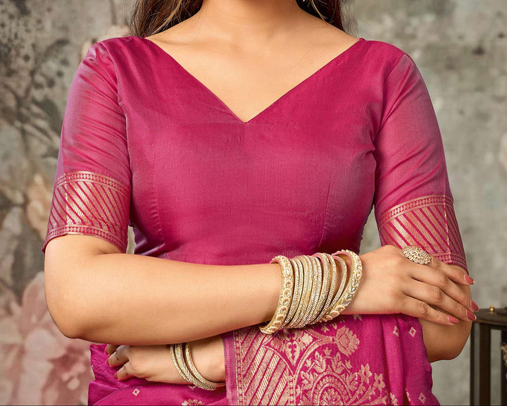Three-quarter view of model in magenta Banarasi silk saree with gold bangles and jhumkas