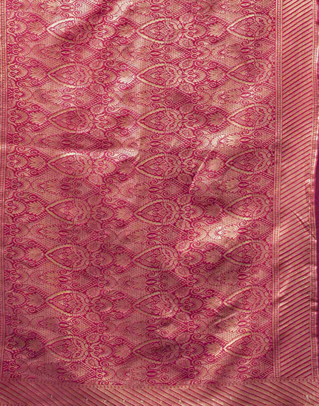 Seated close-up of model in magenta Banarasi silk saree with pearl and gold bangles and ring
