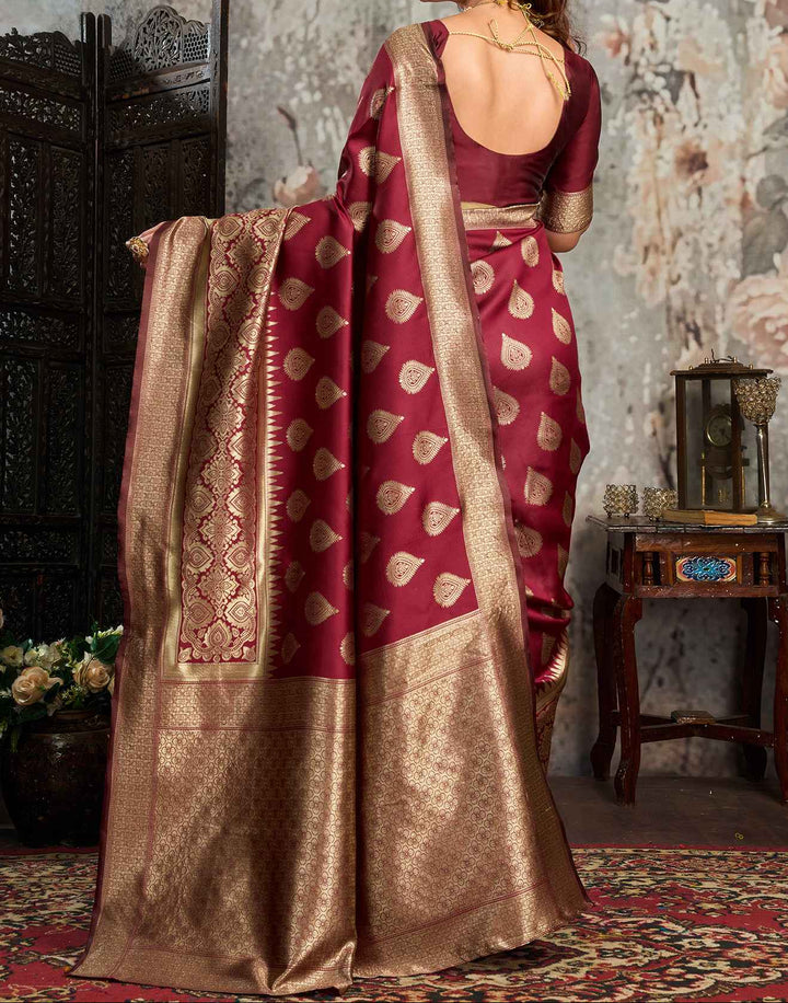 Seated full view of model in maroon Banarasi silk saree with gold zari mango buttas and antique gold jaal pallu spread