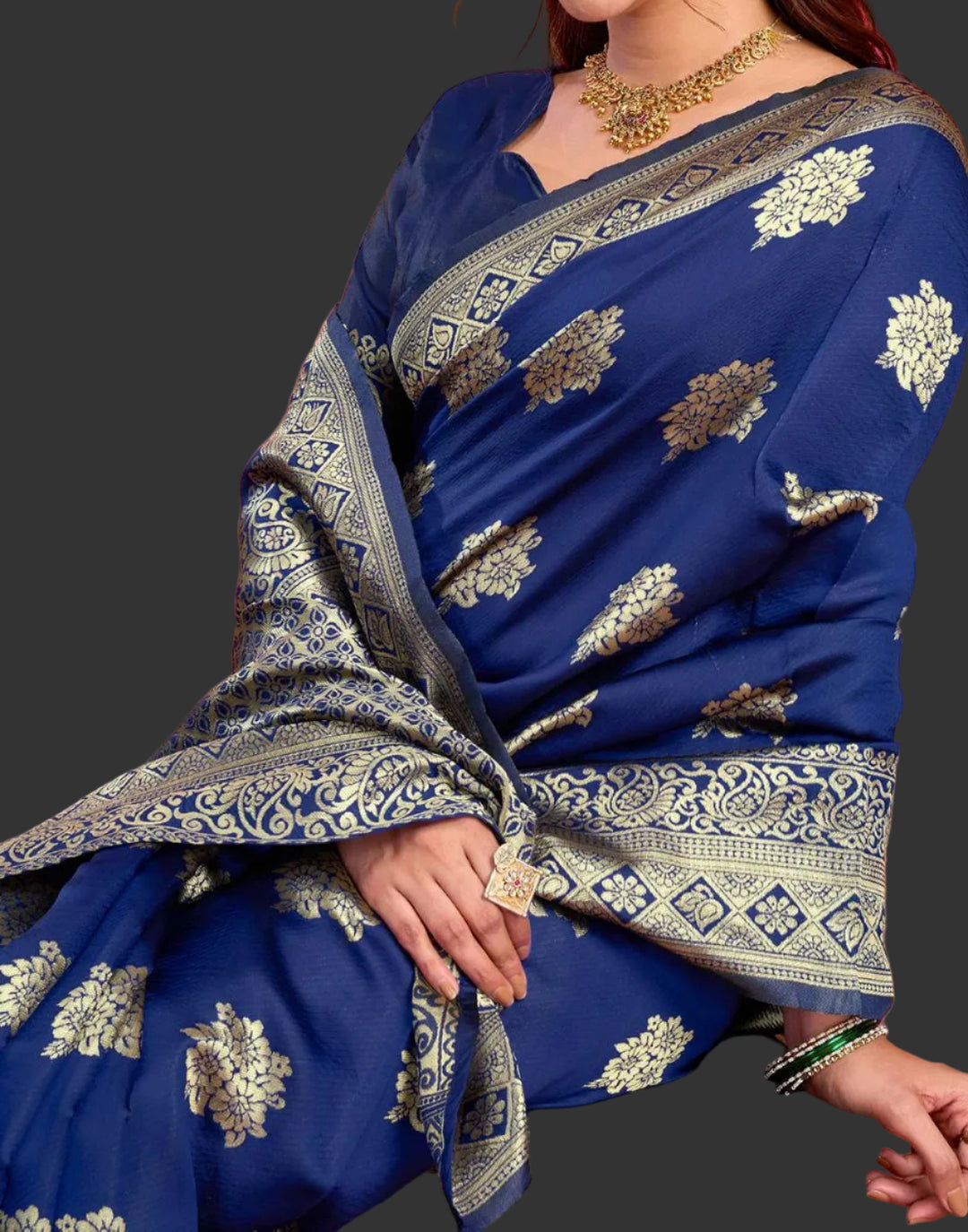 Seated close-up of model in royal blue Banarasi silk saree with gold jhumkas and temple necklace