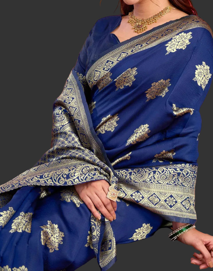 Seated close-up of model in royal blue Banarasi silk saree with gold jhumkas and temple necklace