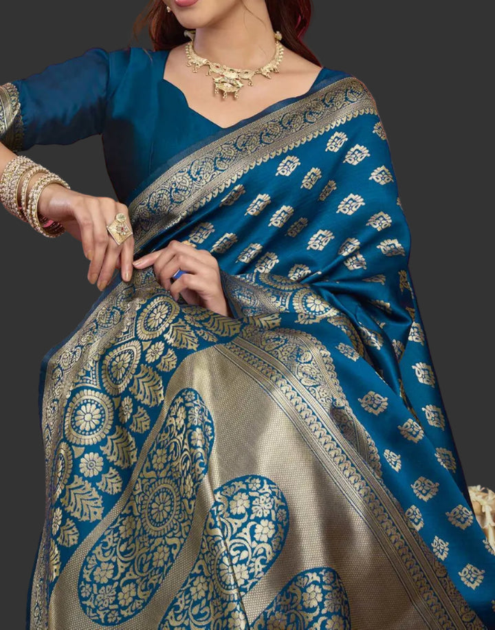 Seated close-up of model in peacock blue Banarasi silk saree with chandelier jhumkas and gold bangles