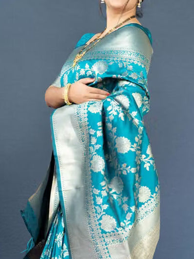 Model seated wearing teal Banarasi silk saree - full spread showing silver zari pallu