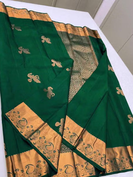Close-up of emerald green Kanjipuram silk saree showing peacock gold zari buttas and broad zari border